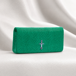 Green clutch bag with a silver emblem on a white fabric background