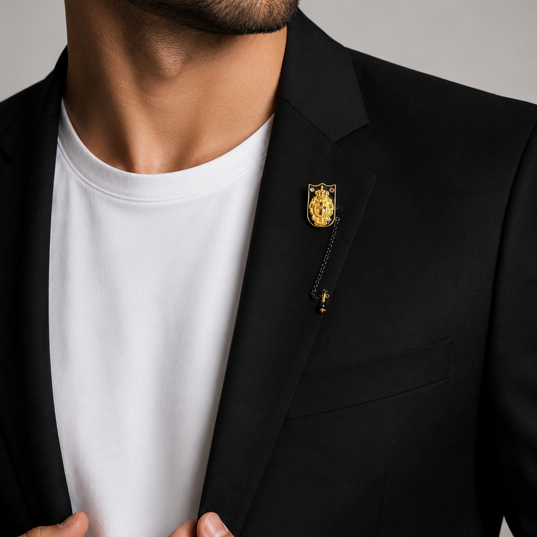 Man wearing a black blazer with a gold pin on a gray background
