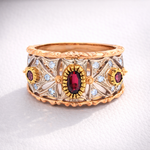 Gold ring with red gemstones and diamond accents on a white background